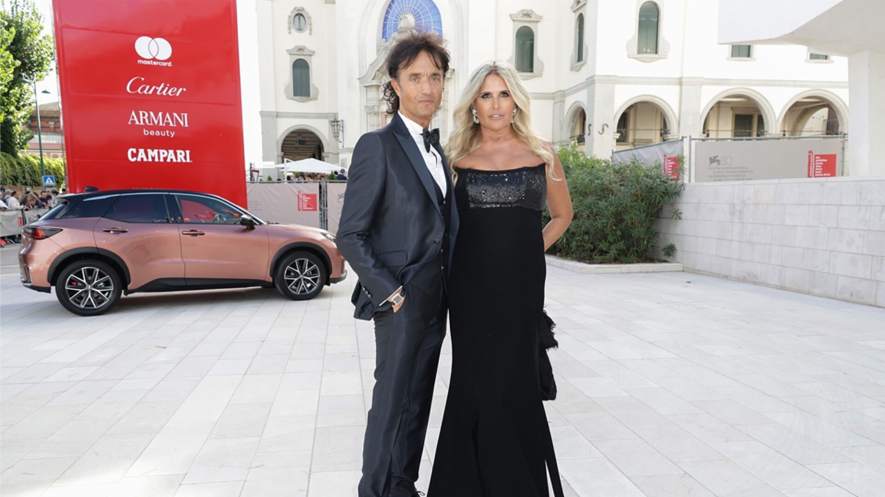 Tiziana Rocca und Giulio Base stehen bei den Filmfestspielen von Venedig vor einem Lexus